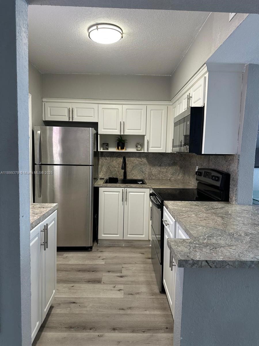 20201 Northeast 29th Court, Unit D335 Aventura, FL 33180 - Photo 6 of 12 a kitchen with granite countertop a refrigerator stove top oven and sink