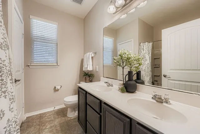 a bathroom with a double vanity sink toilet and a mirror