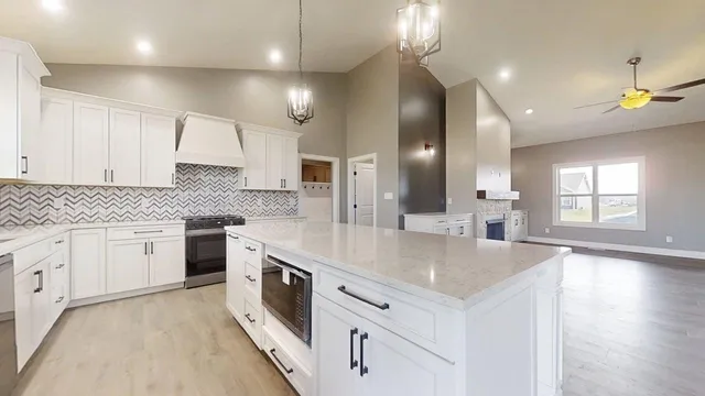 a large white kitchen with a large island oven a stove and white cabinets with wooden floor