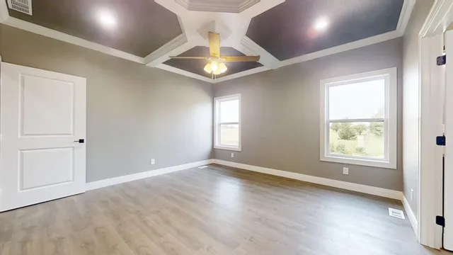 an empty room with wooden floor and windows