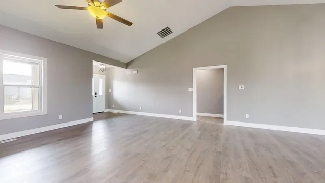 an empty room with wooden floor and windows