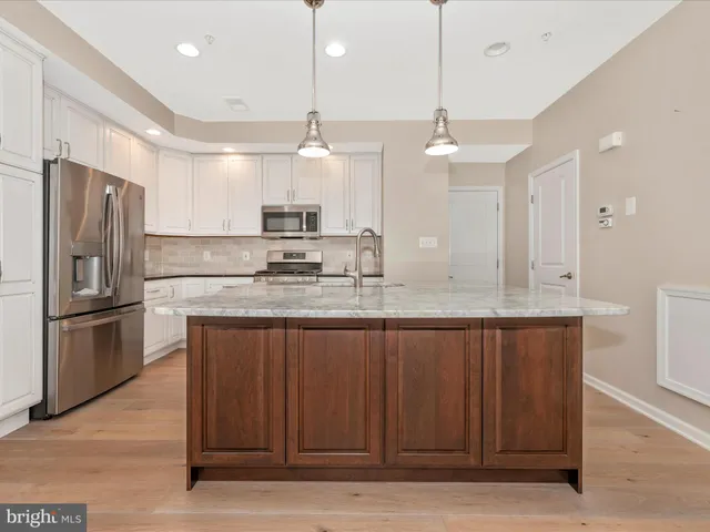 a kitchen with stainless steel appliances granite countertop a refrigerator and a stove top oven