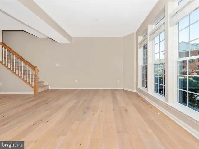 a view of an empty room with wooden floor and stairs