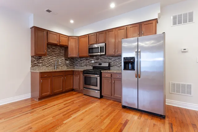 a kitchen with stainless steel appliances granite countertop a refrigerator a sink dishwasher a stove with wooden floor