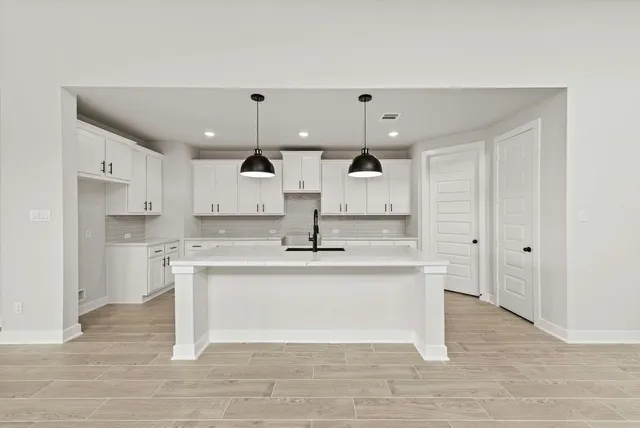 a large white kitchen with kitchen island a sink a stove and a refrigerator