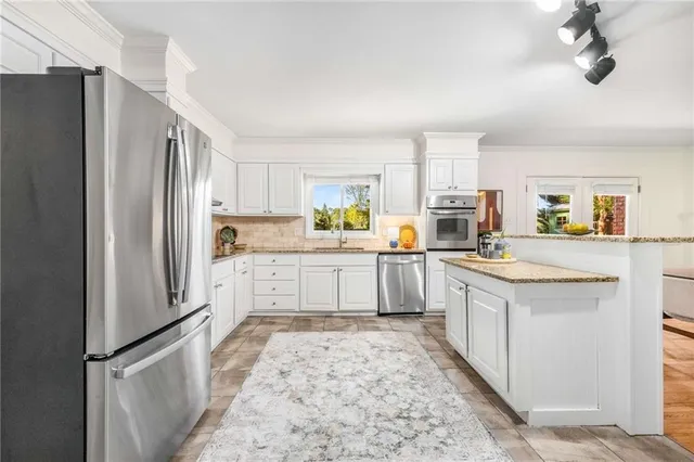 a kitchen with stainless steel appliances granite countertop a refrigerator a stove and a sink