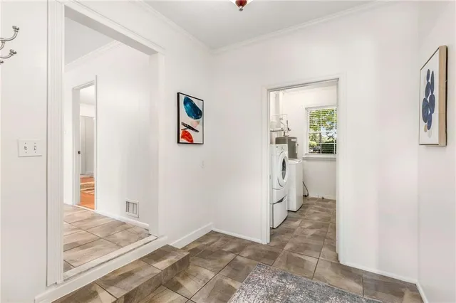 a view of a hallway to a livingroom with wooden floor and a refrigerator