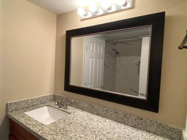 a bathroom with a granite countertop sink and a mirror