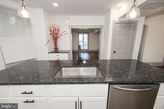 a kitchen with granite countertop a sink and a white cabinets