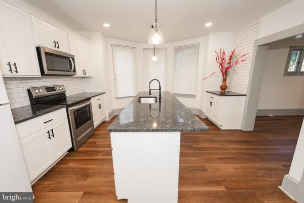 a kitchen with stainless steel appliances granite countertop a sink a stove top oven a counter space and cabinets