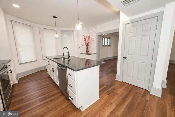 a kitchen with granite countertop a sink stove and wooden floor