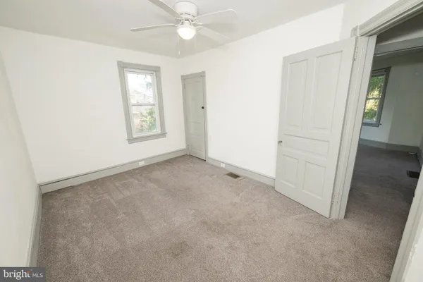 an empty room with windows and fan