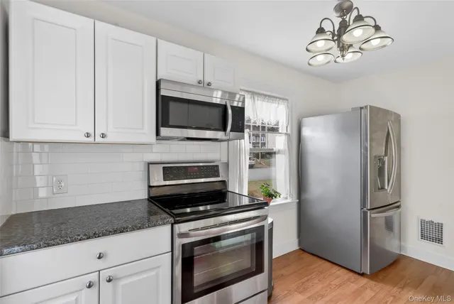 a kitchen with stainless steel appliances granite countertop a stove a microwave a refrigerator a sink and dishwasher with wooden floor