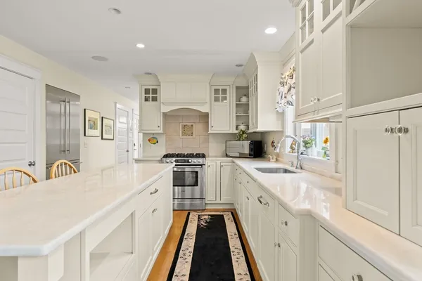 a large white kitchen with stainless steel appliances lots of counter space and wooden floor