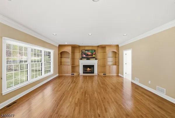 a big room with wooden floor fireplace and windows