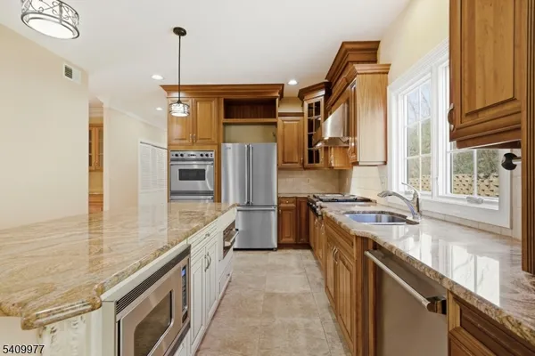 a kitchen with stainless steel appliances granite countertop a stove a sink and a refrigerator