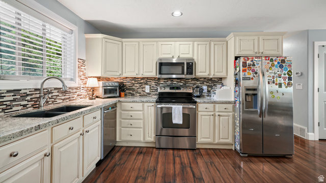 141 East 550 North Springville, UT 84663 - Photo 8 of 28 Kitchen featuring cream cabinetry, stainless steel appliances, granite countertops, mosaic tile backsplash, and walnut wood-finish flooring