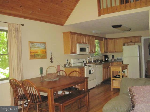 688 Fern Valley Way Springfield, WV 26763 - Photo 9 of 22 a kitchen with stainless steel appliances granite countertop a stove a sink dishwasher a dining table and chairs with wooden floor