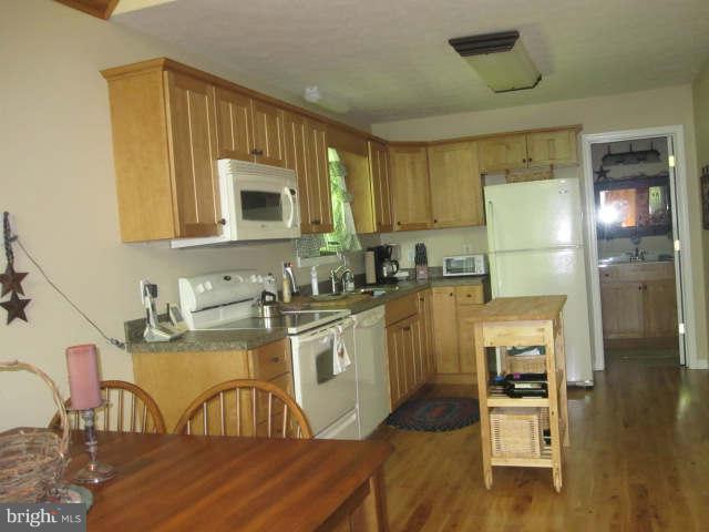 688 Fern Valley Way Springfield, WV 26763 - Photo 10 of 22 a kitchen with stainless steel appliances granite countertop a refrigerator a stove top oven and a dining table with wooden floor