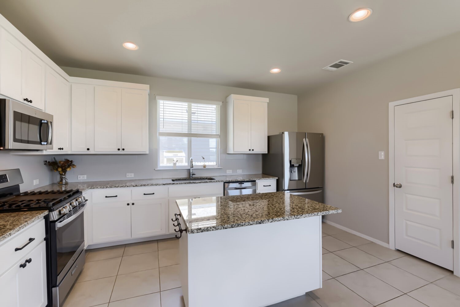 1310 Goforth Road Kyle, TX 78640 - Photo 12 of 24 Contemporary kitchen featuring white cabinetry, a granite-topped island, stainless steel appliances, recessed lighting, and tile flooring