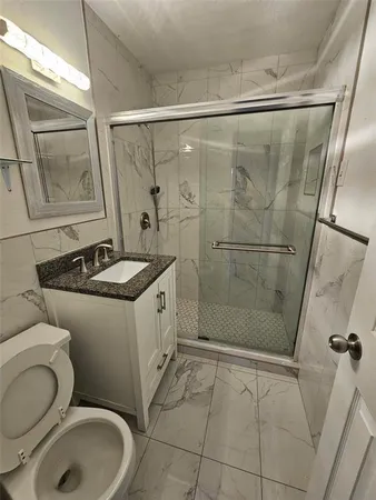 a bathroom with a granite countertop sink toilet and shower