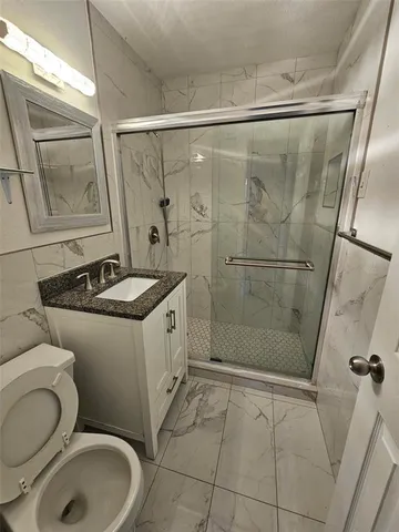 a bathroom with a granite countertop sink toilet and shower