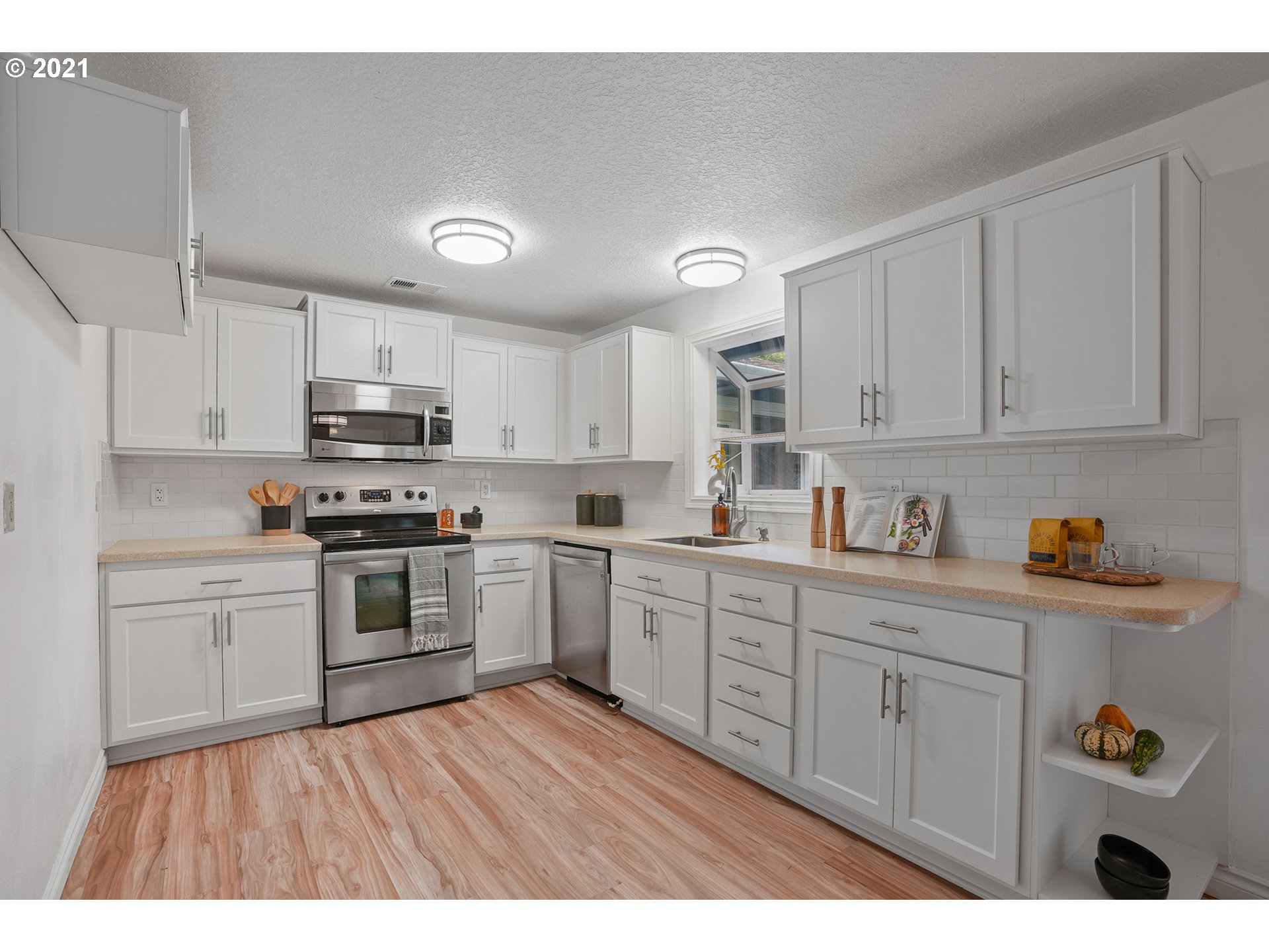 45 Southwest Collins Street Portland, OR 97219 - Photo 8 of 28 a kitchen with stainless steel appliances granite countertop a sink dishwasher stove and white cabinets with wooden floor