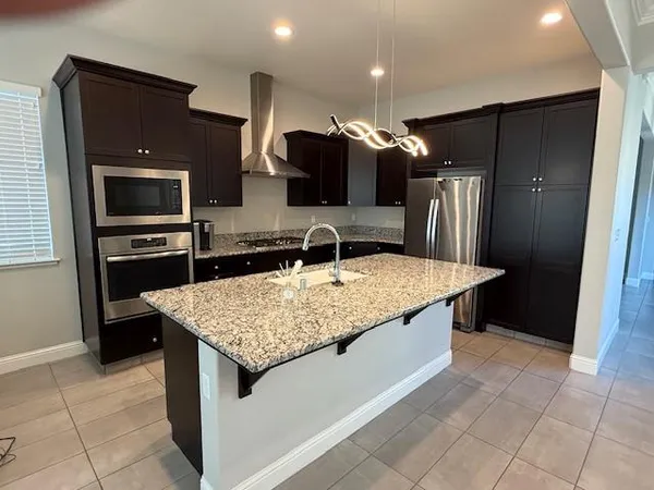 a kitchen with stainless steel appliances granite countertop a sink and a refrigerator
