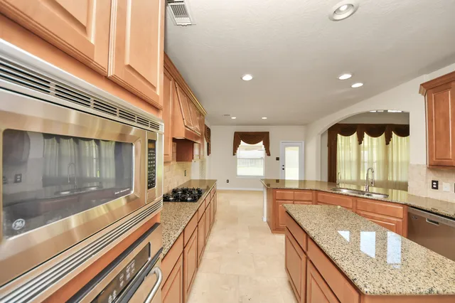 a large white kitchen with stainless steel appliances granite countertop a refrigerator and a stove top oven