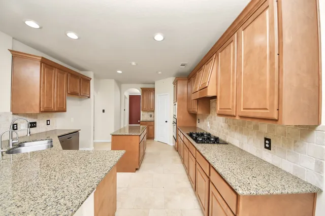 a living room with stainless steel appliances furniture a rug and a kitchen view