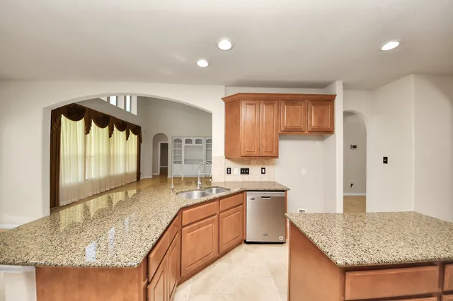 a spacious bathroom with a granite countertop sink a mirror a bathtub and shower