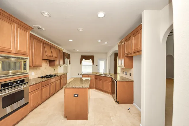 a large kitchen with stainless steel appliances granite countertop a stove and a sink