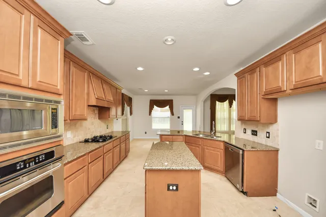 a kitchen with stainless steel appliances granite countertop a sink a stove and a refrigerator