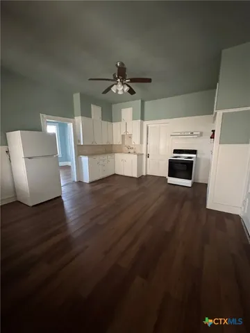 a view of a livingroom with furniture wooden floor ceiling fan and a kitchen