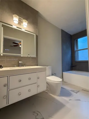 a bathroom with a granite countertop toilet sink and mirror