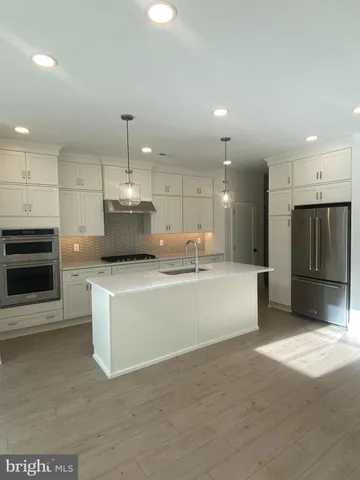 a large kitchen with kitchen island a stove a oven a sink and a refrigerator