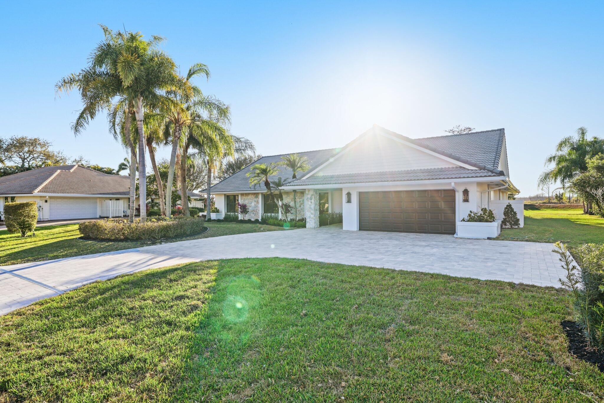24 Dunbar Road Palm Beach Gardens, FL 33418 - Photo 92 of 93 a front view of a house with a yard and palm trees