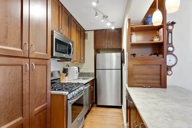 a kitchen with stainless steel appliances granite countertop a refrigerator a stove and a sink with wooden floor