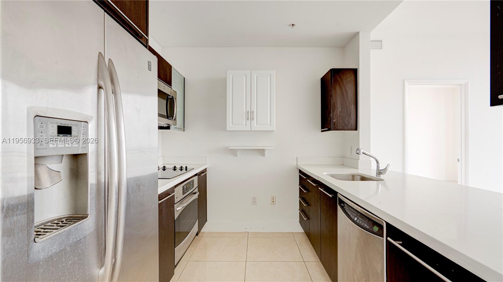 90 Southwest 3rd Street, Unit PH10 Miami, FL 33130 - Photo 17 of 31 a kitchen with stainless steel appliances granite countertop a sink and dishwasher a refrigerator with wooden cabinets