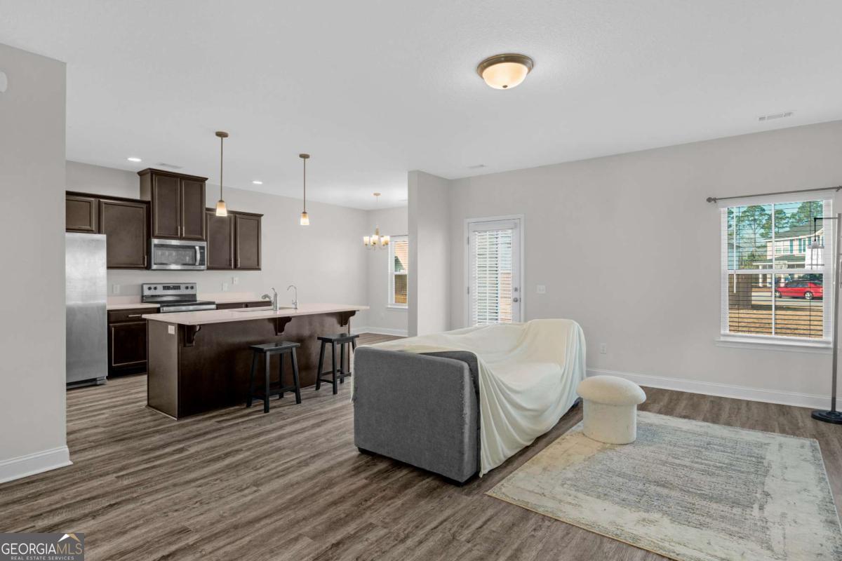 505 Rutledge Drive Hinesville, GA 31313 - Photo 16 of 24 a living room with stainless steel appliances kitchen island granite countertop a couch and wooden floor