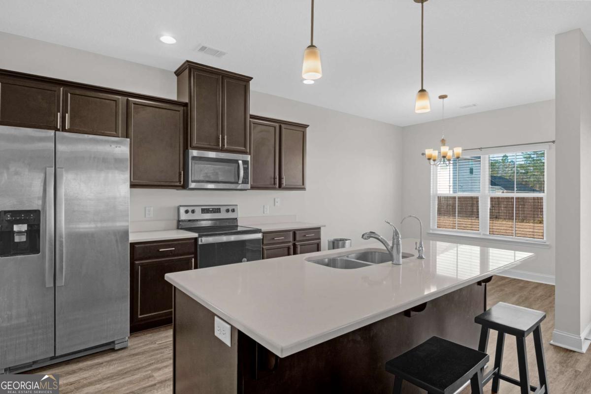 505 Rutledge Drive Hinesville, GA 31313 - Photo 17 of 24 a kitchen with stainless steel appliances granite countertop a refrigerator a sink a stove a dining table and chairs