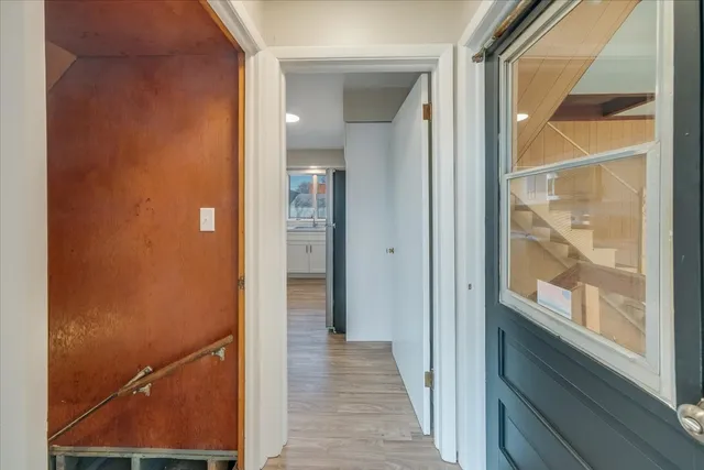 a view of a hallway with wooden floor and a bathroom