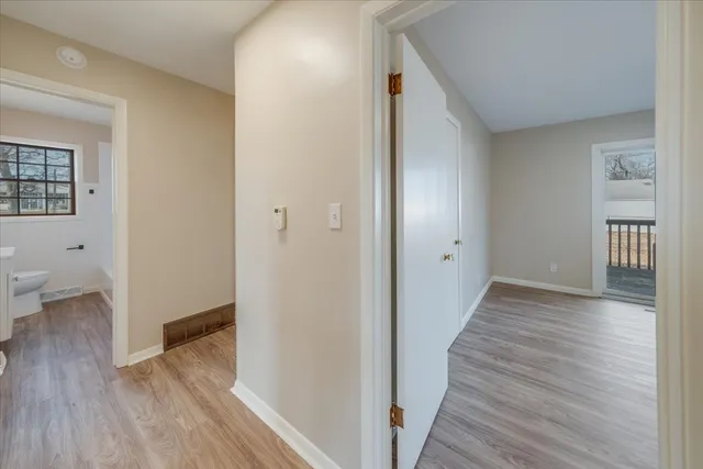 a view of a hallway with wooden floor and a bathroom