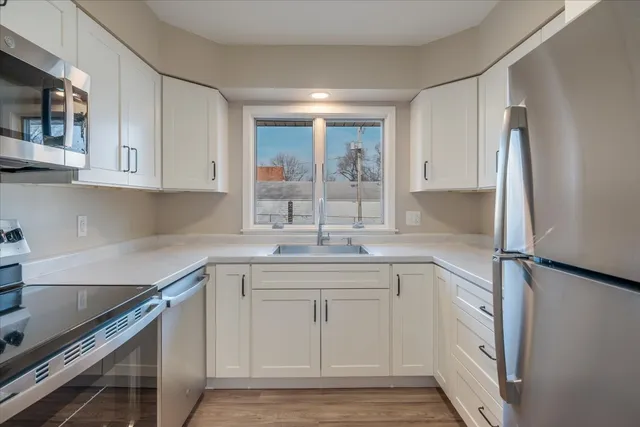 a kitchen with white cabinets and sink