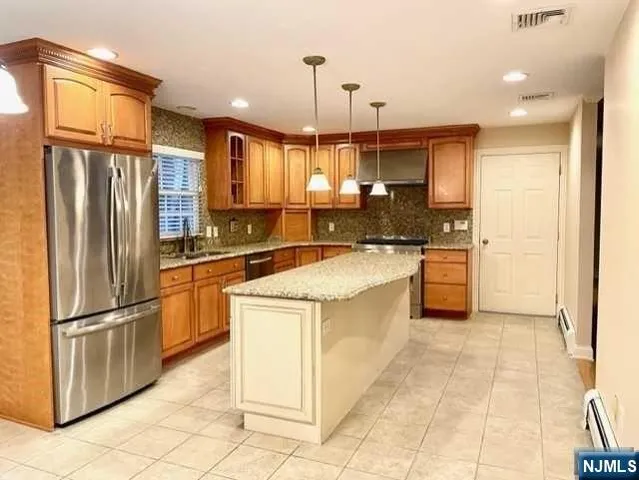 a kitchen with stainless steel appliances granite countertop a refrigerator a sink and white cabinets