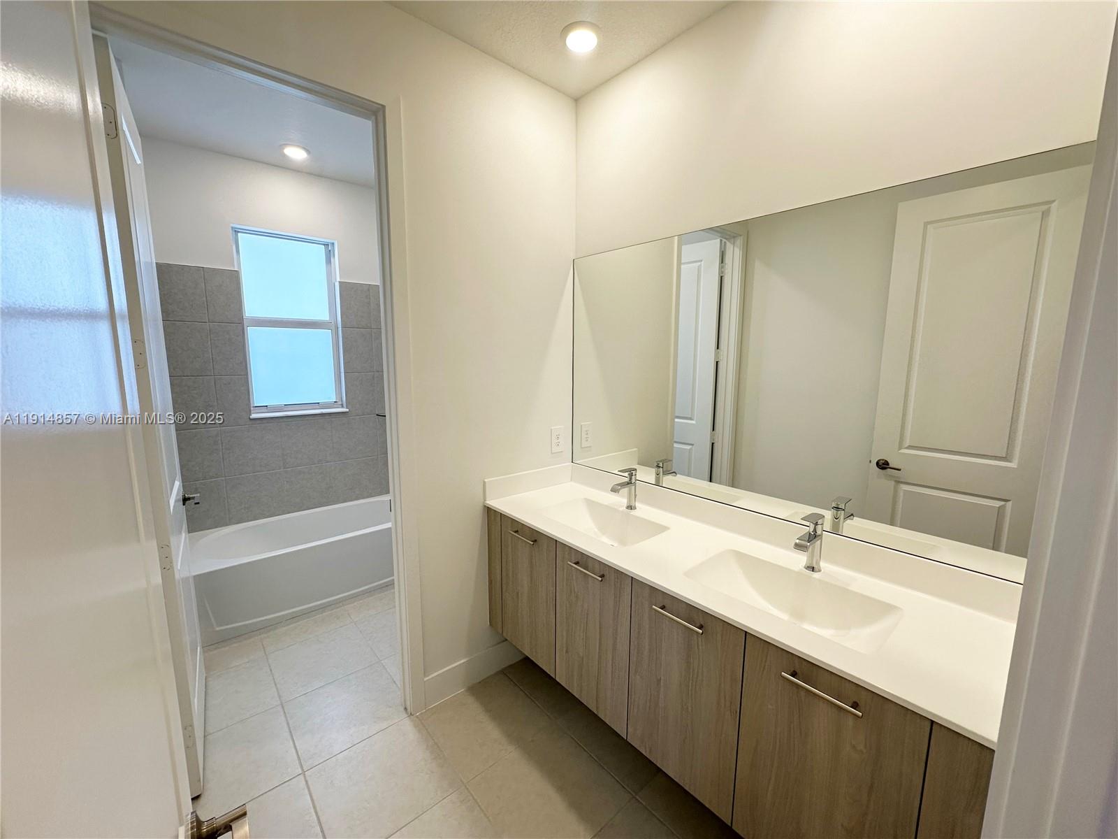 12273 Southwest 44th Street Davie, FL 33330 - Photo 25 of 31 a bathroom with a double vanity sink a mirror and a bathtub