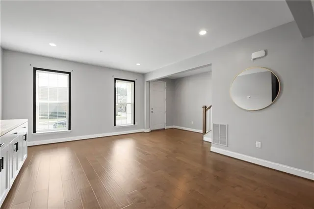 an empty room with wooden floor and windows