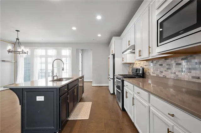 a kitchen with stainless steel appliances granite countertop a sink a stove and a wooden floors
