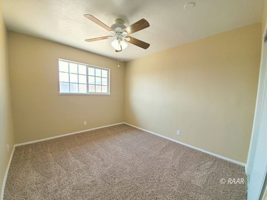 1037 South Ranger Street Ridgecrest, CA 93555 - Photo 11 of 26 an empty room with a chandelier fan and windows