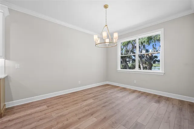 a view of a big room with wooden floor chandeliers and kitchen view